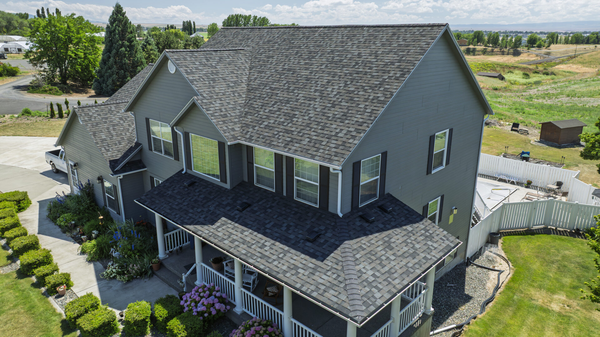 New residential roof replacement on a two story gray house in the mountainous area of Lewiston ID / Spokane WA