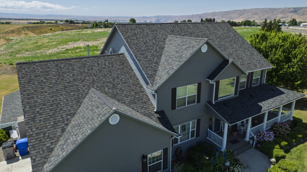 New residential roof replacement on a two story gray house in the mountainous area of Lewiston ID / Spokane WA