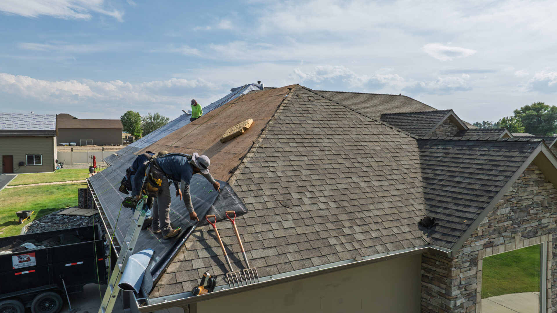 Russell Quality Roofing completing a roof replacement project in the Lewiston/Spokane area. Three men on a roof working on a roof replacement.