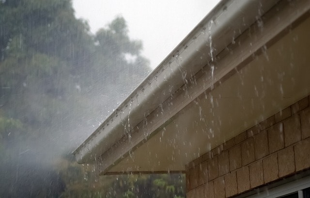 Heavy Rain Delay in Your Roof Replacement Timeline - Rain against a residential roof with gutters