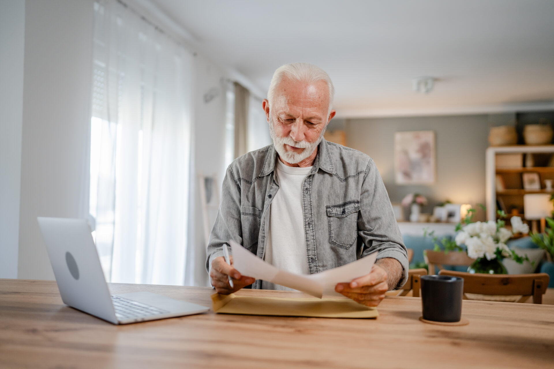 senior caucasian man open mail letter sign document envelope while sit at the table at home receiving bank statement loan approval contract or business insurance news invitation