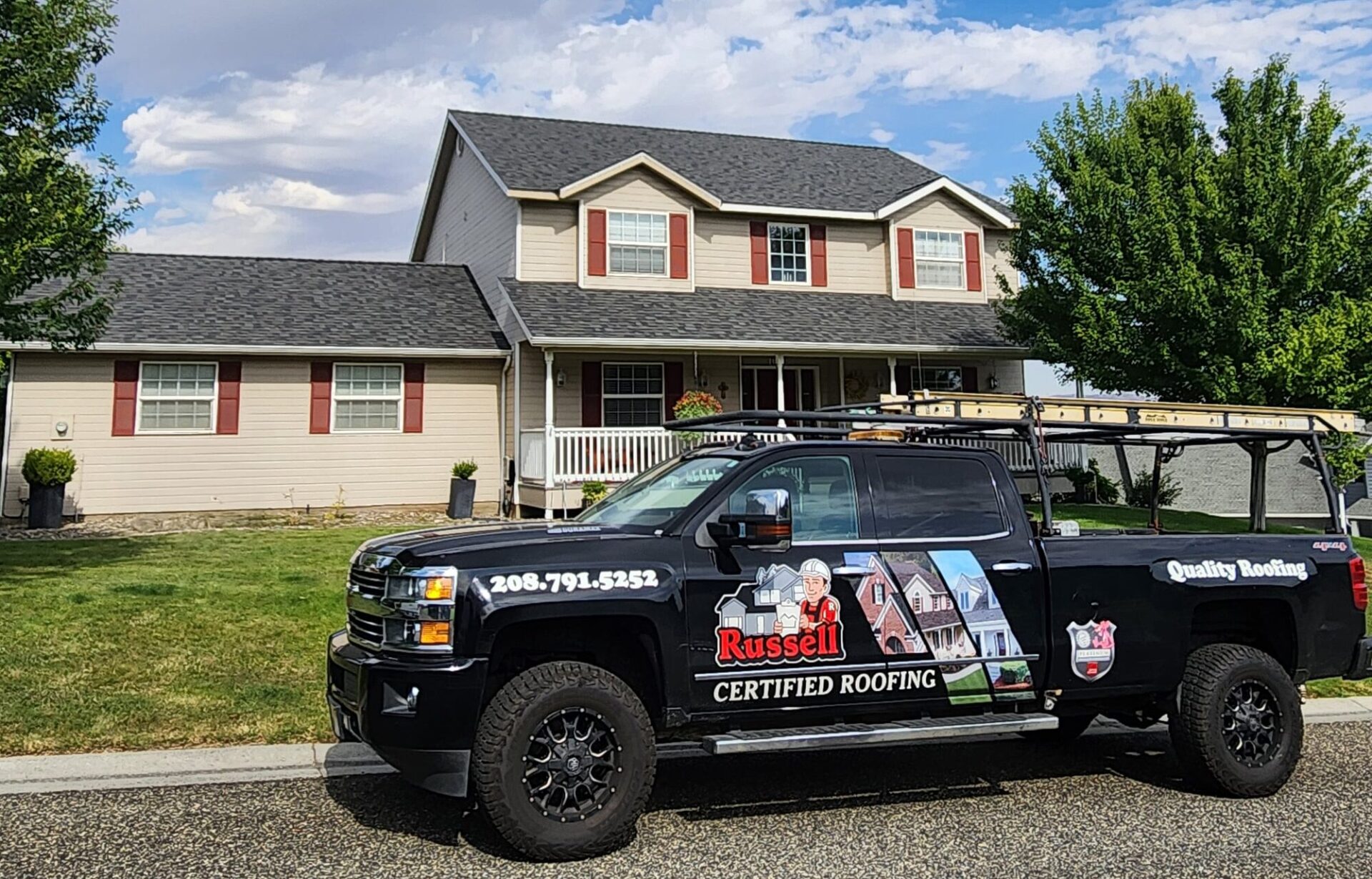 Street view photo of a Russell Quality Roofing truck next to a completed roofing project for a residential home