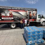 Members of Russell Quality Roofing team standing in front of a company truck with cases of water for their relief donation