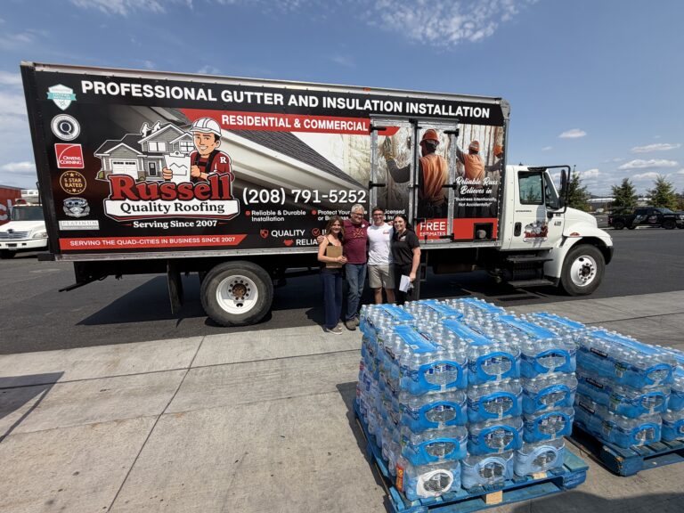 Members of Russell Quality Roofing team standing in front of a company truck with cases of water for their relief donation